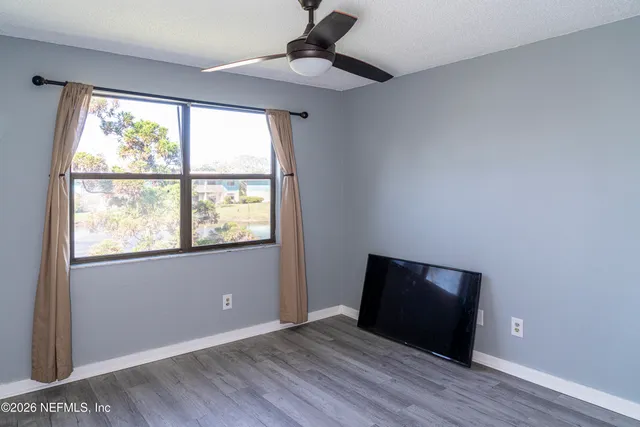 a view of an empty room with wooden floor and a window