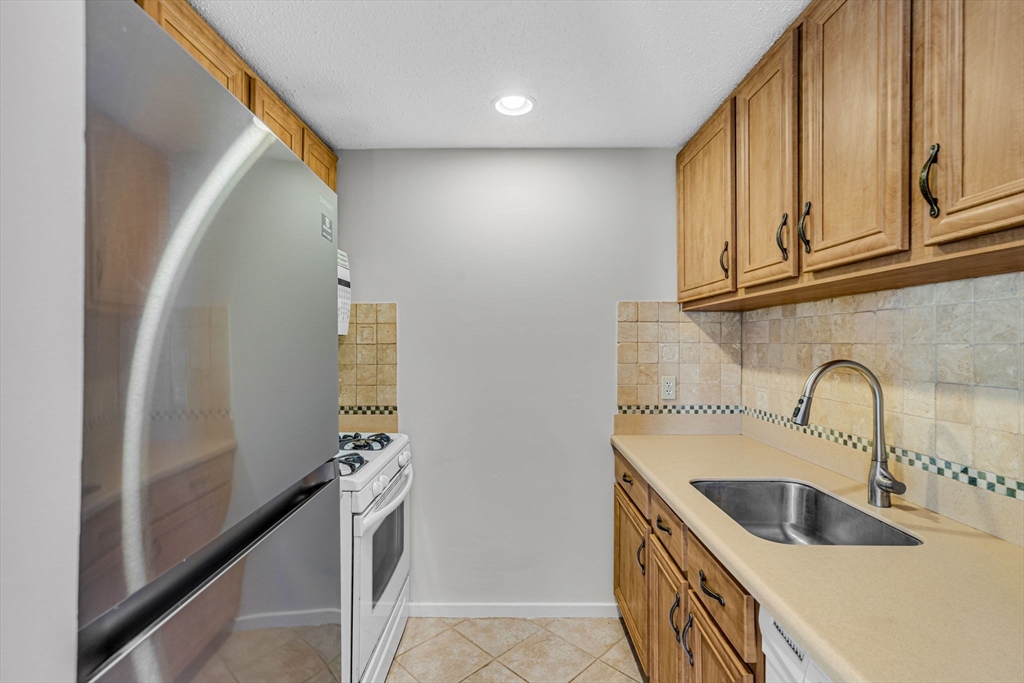 403 Great Road, Unit 5 Acton, MA 01720 - Photo 11 of 25 a kitchen with stainless steel appliances granite countertop a sink and a refrigerator