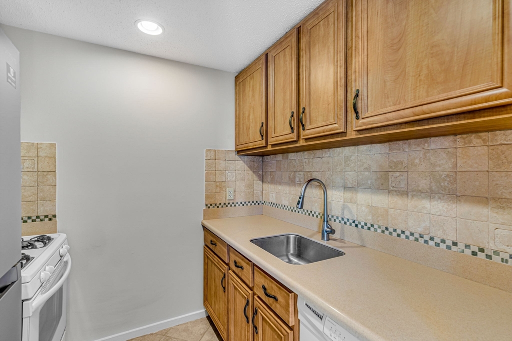 403 Great Road, Unit 5 Acton, MA 01720 - Photo 12 of 25 a kitchen with stainless steel appliances granite countertop a sink a stove and a microwave