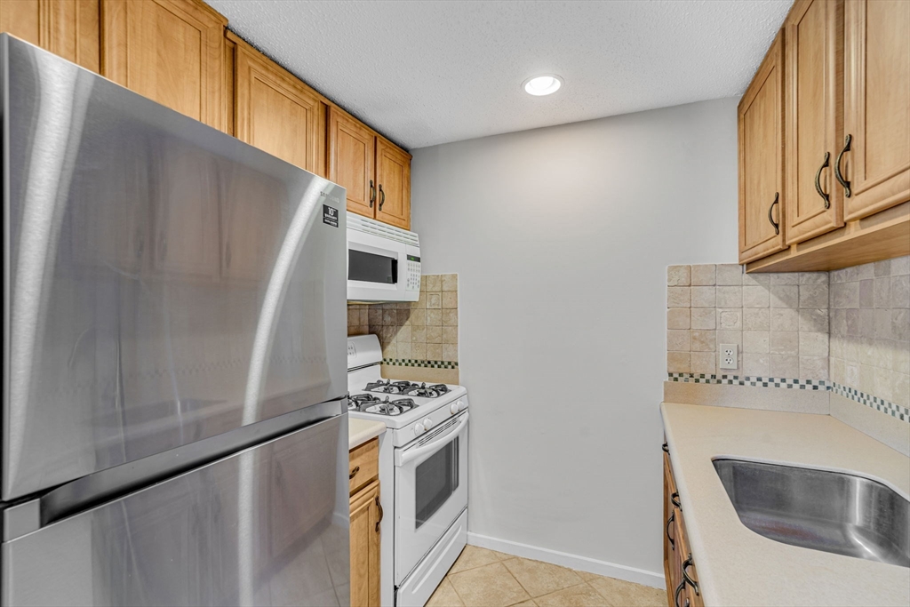 403 Great Road, Unit 5 Acton, MA 01720 - Photo 13 of 25 a kitchen with granite countertop a sink a stove and refrigerator