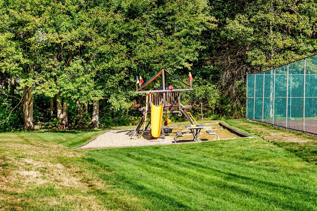 403 Great Road, Unit 5 Acton, MA 01720 - Photo 24 of 25 a view of a backyard with a slide trees and wooden fence