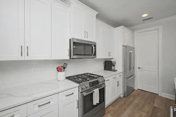 a kitchen with stainless steel appliances white cabinets and a stove a oven with wooden floor