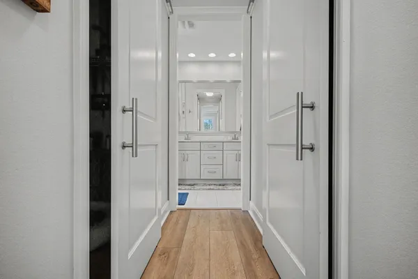a view of a hallway with wooden floor and a bathroom