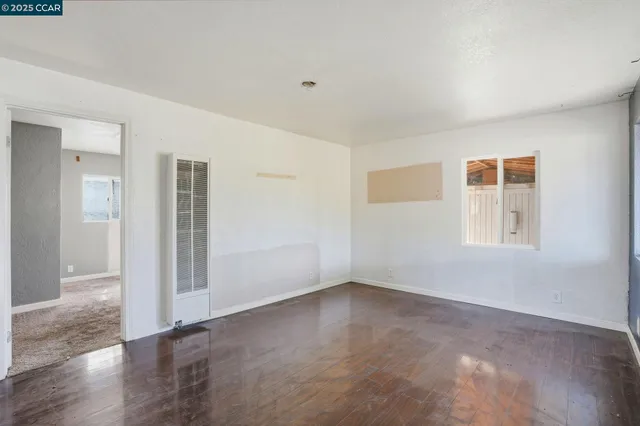 a view of an empty room with wooden floor and a window