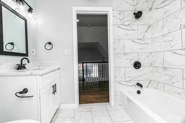 a bathroom with a tub a sink and mirror