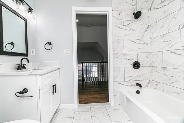 a bathroom with a tub a sink and mirror