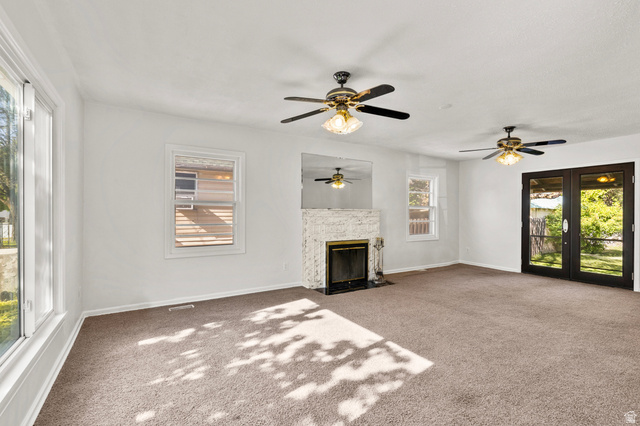 658 North 100 East Logan, UT 84321 - Photo 6 of 26 Spacious interior room featuring light-toned carpeting, a white brick fireplace with a dark firebox, and two ceiling fans with integrated lighting