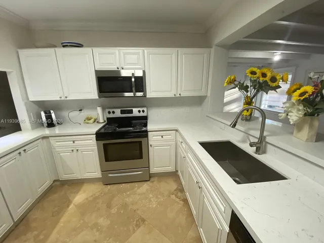 a kitchen with stainless steel appliances kitchen island granite countertop a sink a stove and a sink
