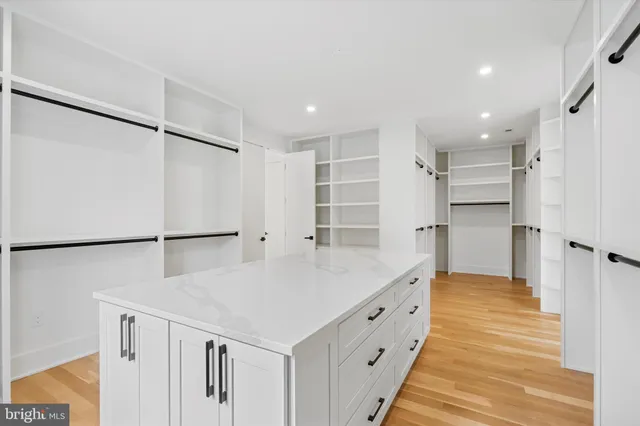 a large white kitchen with white cabinets and wooden floor