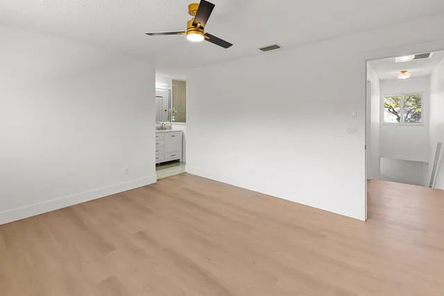 a large white kitchen with a refrigerator a stove a microwave and a dining table