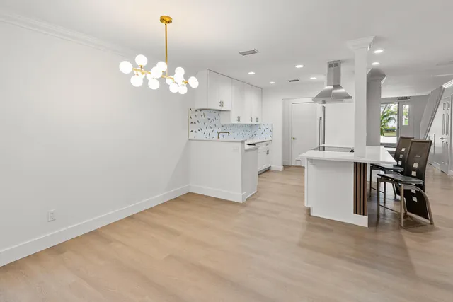 a kitchen with stainless steel appliances granite countertop a stove a sink dishwasher a dining table and chair with wooden floor