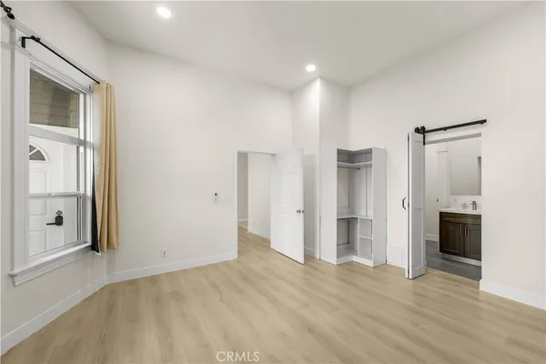a view of an empty room with wooden floor and a kitchen