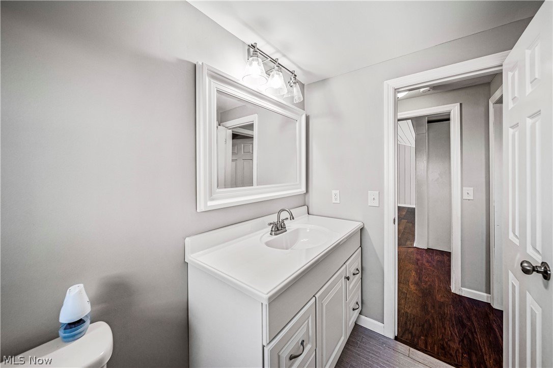 3395 Maple Road Jefferson, OH 44047 - Photo 10 of 36 Bathroom with vanity with extensive cabinet space, toilet, and hardwood / wood-style flooring