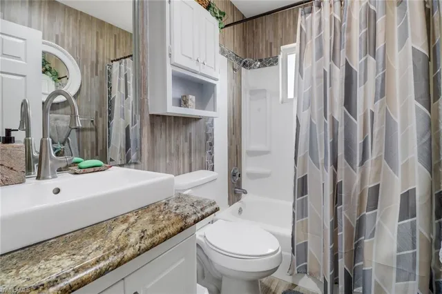 a bathroom with a granite countertop sink a toilet and shower