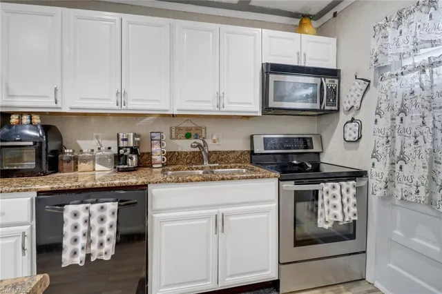 a kitchen with stainless steel appliances granite countertop white cabinets a sink and dishwasher