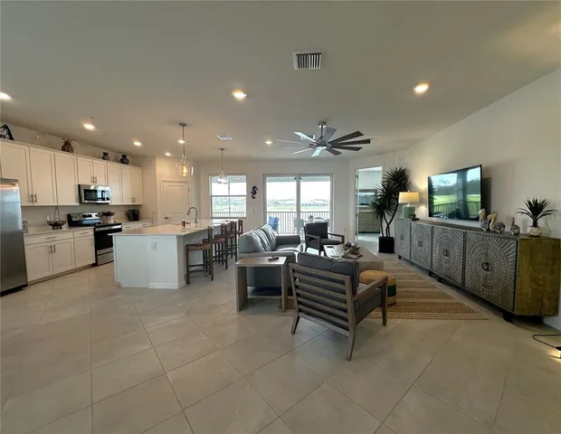 a living room with furniture kitchen view and a wooden floor