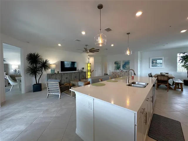 a large kitchen with sink a counter top space and living room view
