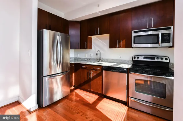 a kitchen with stainless steel appliances wooden floors and wooden cabinets