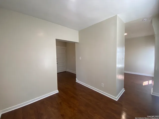an empty room with wooden floor & windows