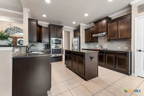 a kitchen with stainless steel appliances granite countertop a stove a sink and a refrigerator
