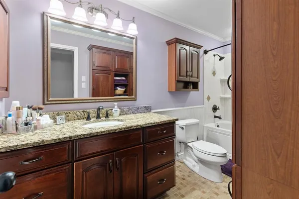 a bathroom with a granite countertop toilet sink and mirror
