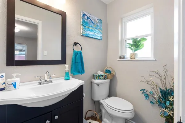 a bathroom with a toilet a sink a window and a mirror