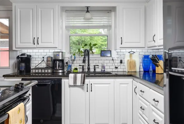 a kitchen with granite countertop white cabinets and appliances
