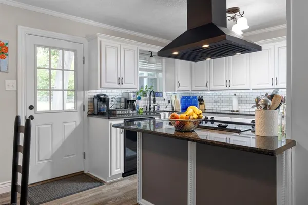 a kitchen with stainless steel appliances white cabinets a sink a stove a dining table and chairs