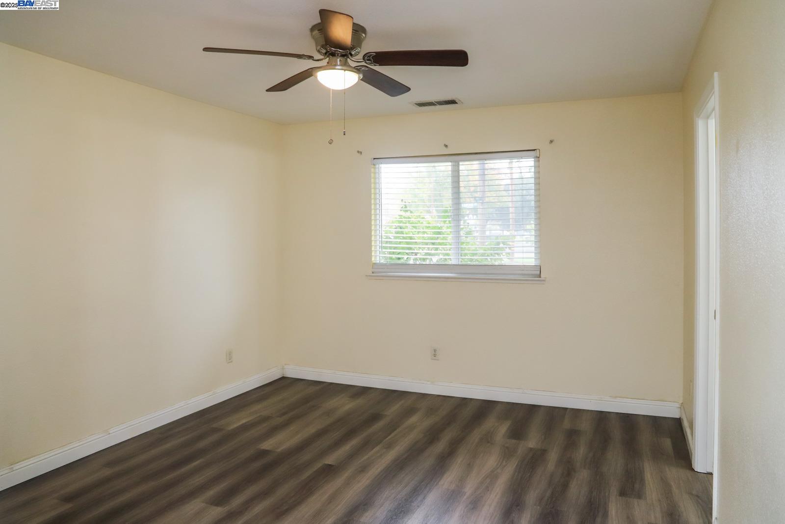 4295 North Archie Avenue Fresno, CA 93726 - Photo 7 of 23 an empty room with wooden floor ceiling fan and windows