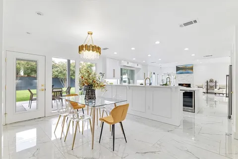 a dining room filled chandelier and kitchen view