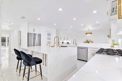 a kitchen with stainless steel appliances kitchen island granite countertop a sink and chairs