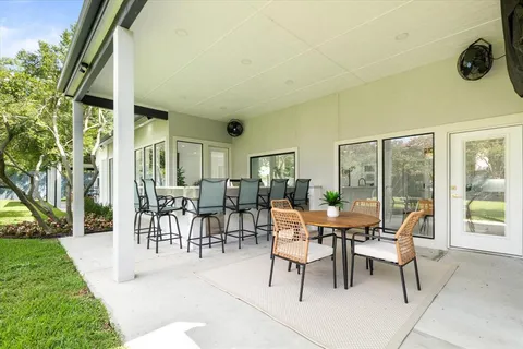 a view of swimming pool with lawn chairs and large trees