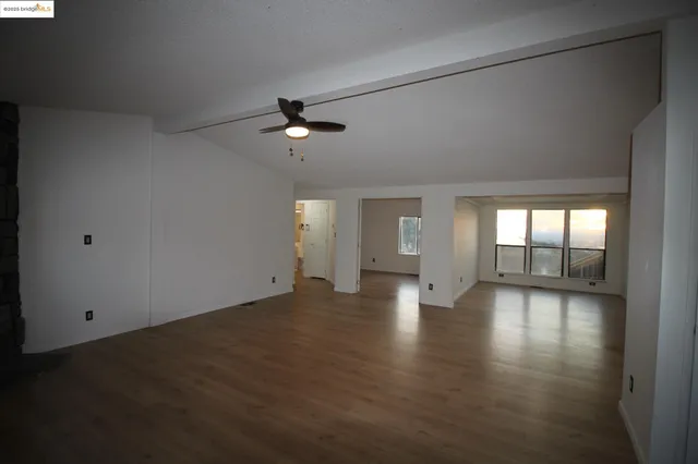 a view of an empty room with a window and wooden floor