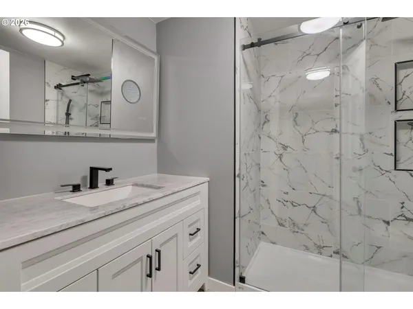 a bathroom with a granite countertop sink a mirror and shower