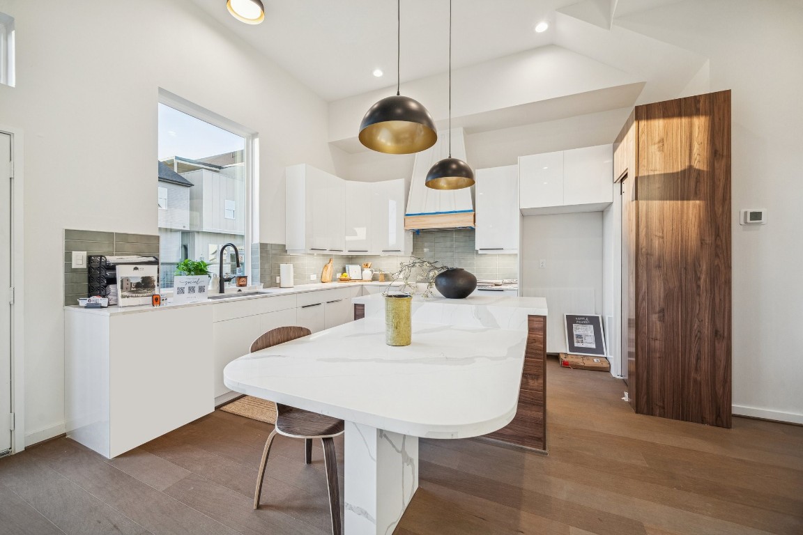 3903 Yale Street Houston, TX 77018 - Photo 4 of 45 A modern kitchen with white cabinets, a large island, and wooden accents. Natural light fills the space.