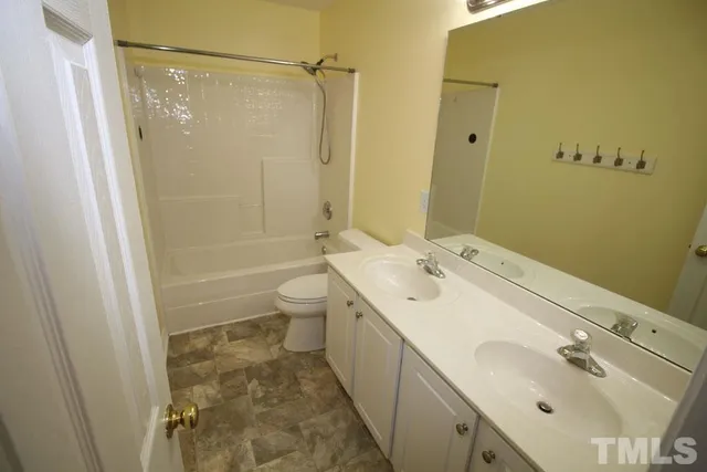 a spacious bathroom with a double vanity sink toilet mirror and shower