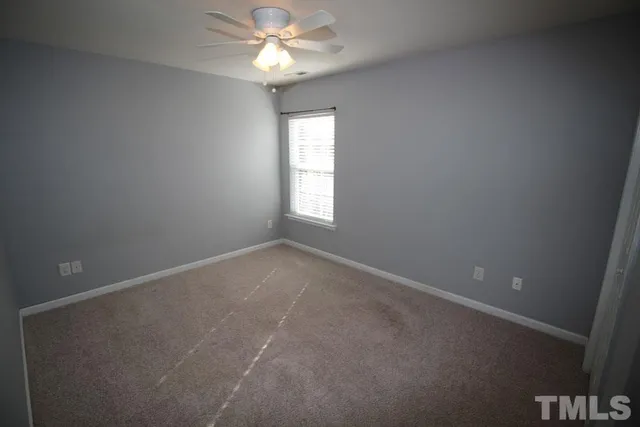 an empty room with a window and ceiling fan