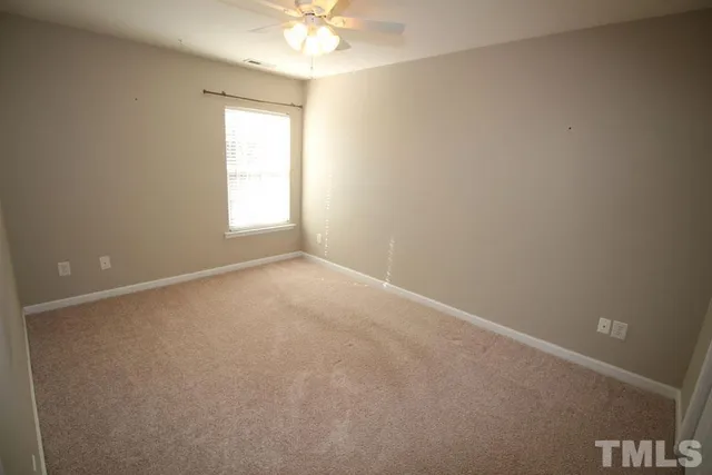 an empty room with a chandelier fan and windows