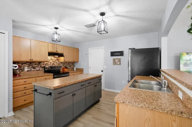 a kitchen with kitchen island granite countertop stainless steel appliances a sink stove and refrigerator