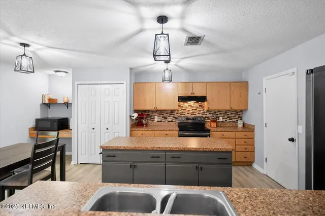 a kitchen with stainless steel appliances kitchen island granite countertop a refrigerator and stove