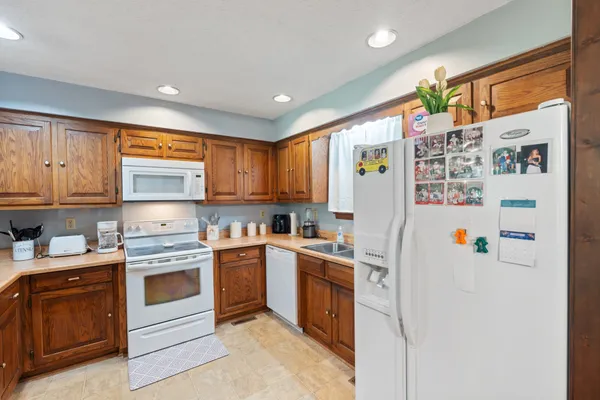 a kitchen with a refrigerator a stove top oven cabinets and a window