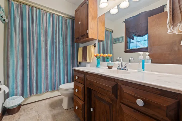 a bathroom with a sink a toilet a mirror and shower curtain