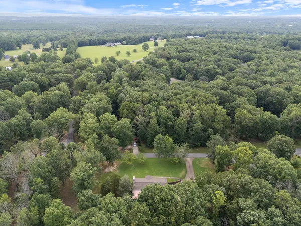 an aerial view of residential house with outdoor space and trees all around