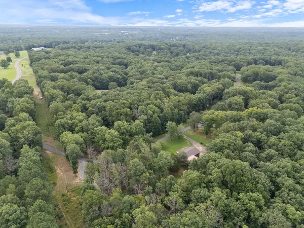 an aerial view of residential house with outdoor space and trees all around