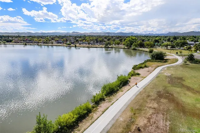 a bed sitting in a spacious bedroom next to a window and a flat screen tv
