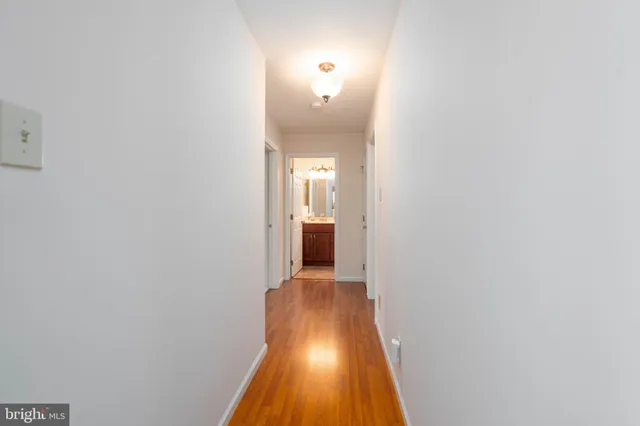 a view of a hallway with wooden floor and a bathroom