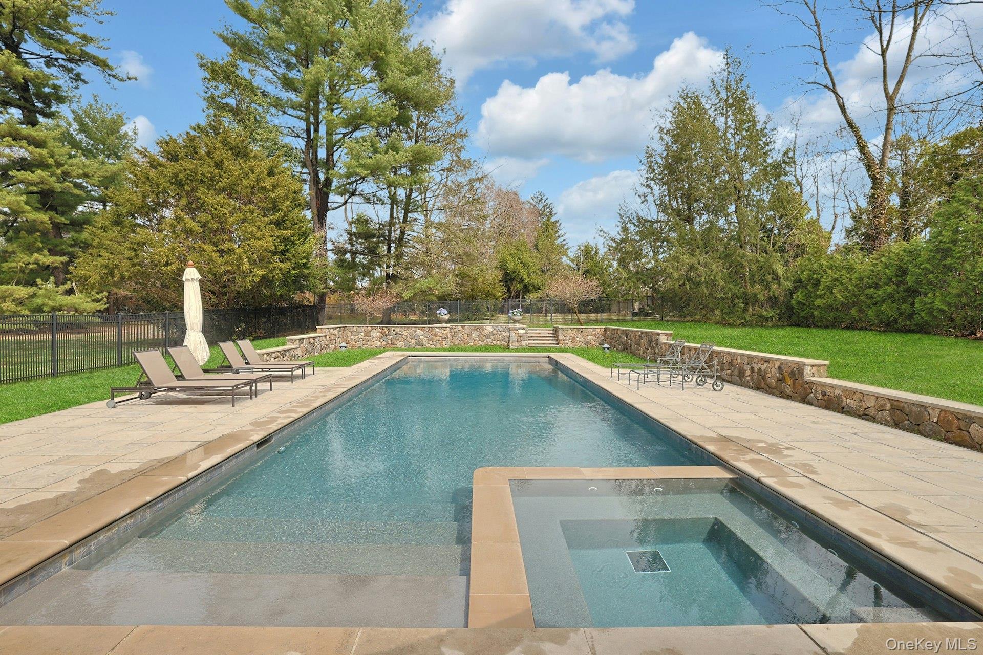 34 Park Road Scarsdale, NY 10583 - Photo 44 of 49 a view of a swimming pool with a chair and trees in the background