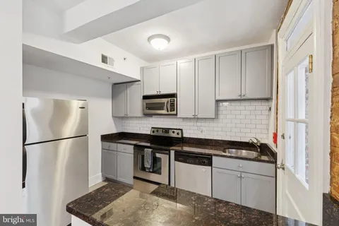 a kitchen with stainless steel appliances granite countertop a refrigerator sink and stove