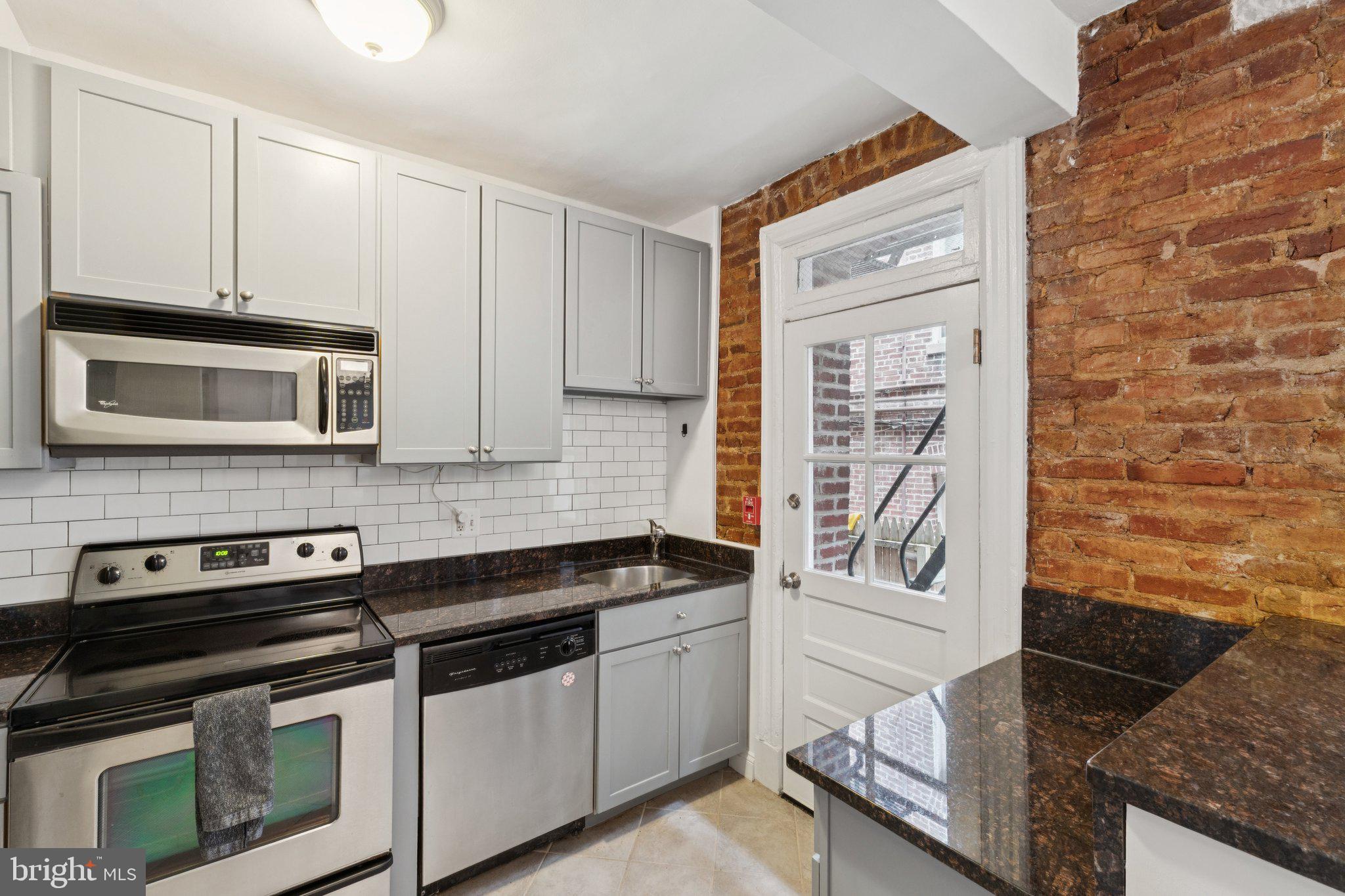 1858 California Street Northwest, Unit 5 Washington, DC 20009 - Photo 12 of 23 a kitchen with stainless steel appliances granite countertop a stove and a microwave