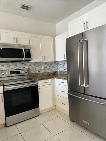a kitchen with granite countertop a refrigerator and a stove top oven